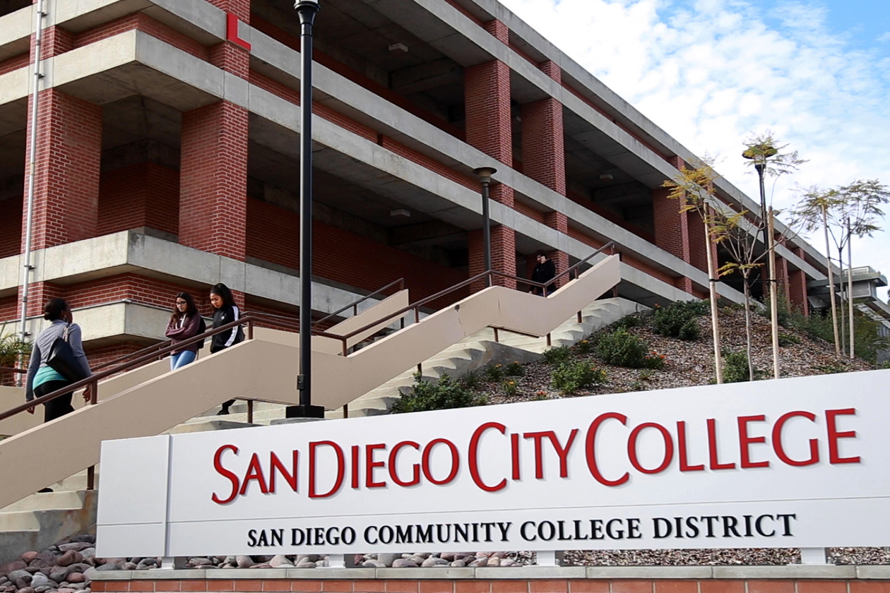 Large San Diego City College sign in foreground with stairs and building behind.