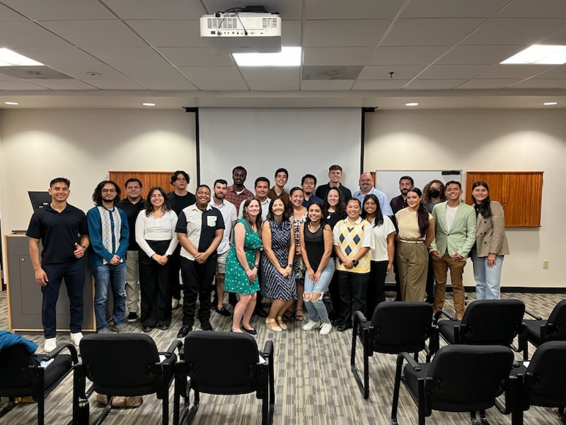 STEM Pathways Scholars 23 in total and 3 staff members stand in front of the room screen to take a picture. 